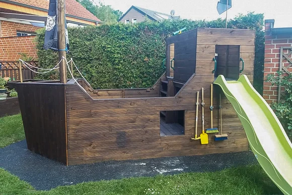 Ein Spielplatz im Garten, der wie ein Piratenschiff gebaut ist.